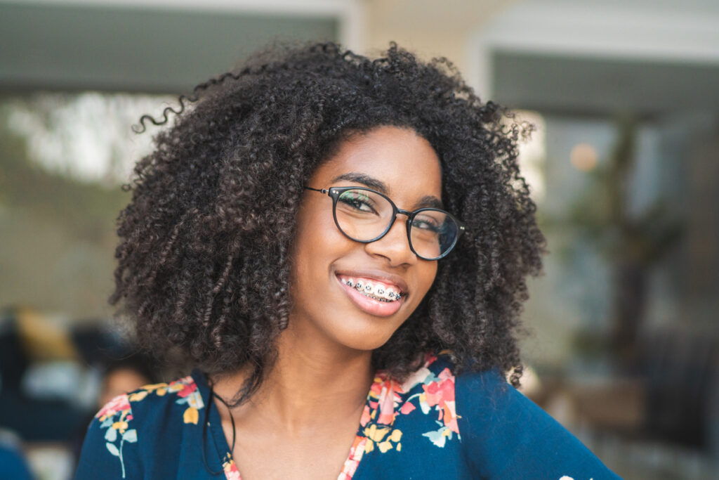 Photogenic teen with braces and glasses smiling with full curly hair