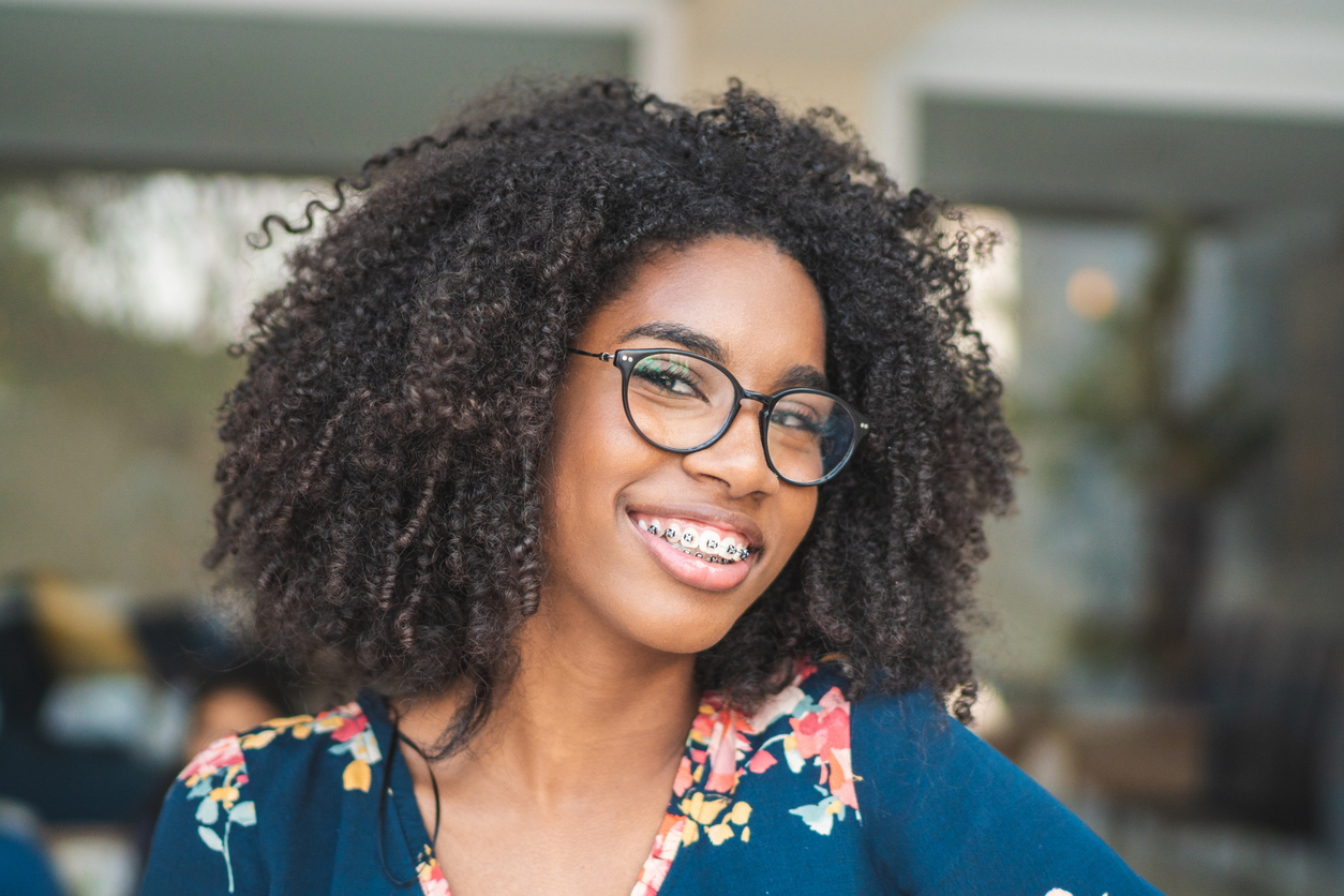 Photogenic teen with braces and glasses smiling with full curly hair