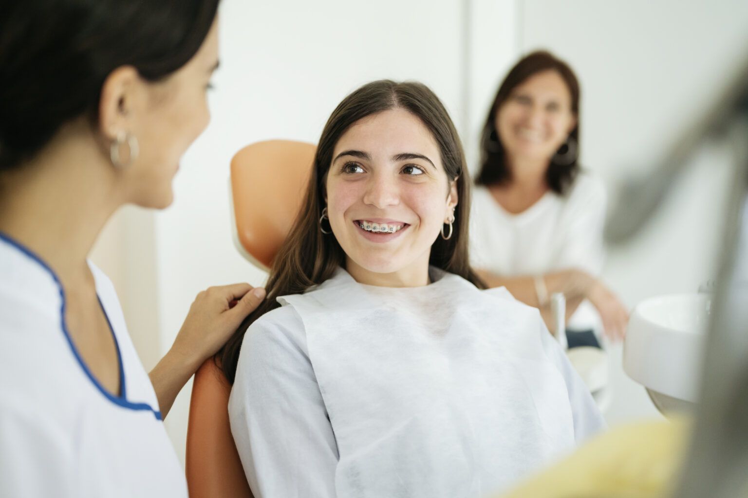 Happy Teenage Patient Smiling At Female Dentist